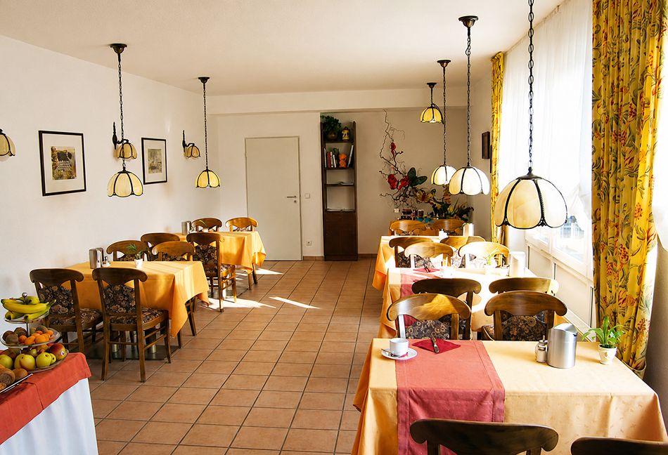 Frühstücksraum mit Tischen, Stühlen und einem Buffet